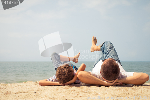 Image of Father and son playing on the beach at the day time.