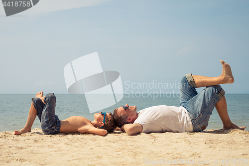 Image of Father and son playing on the beach at the day time.