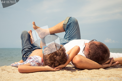 Image of Father and son playing on the beach at the day time.