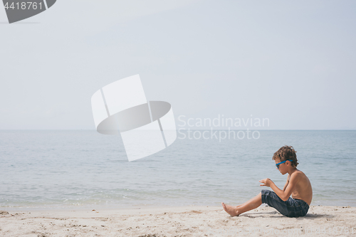 Image of One happy little boy playing on the beach at the day time.