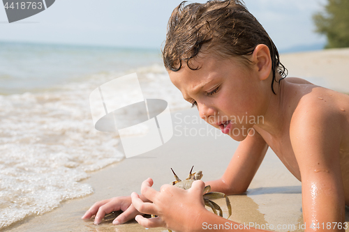 Image of One happy little boy playing on the beach at the day time.