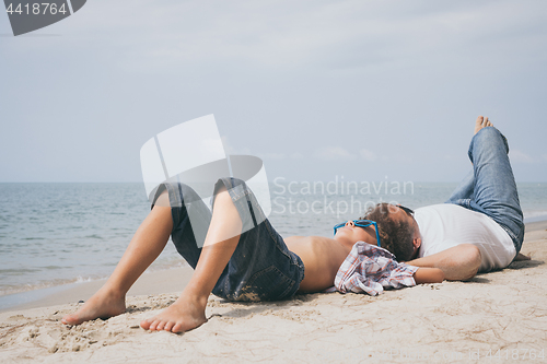 Image of Father and son playing on the beach at the day time.