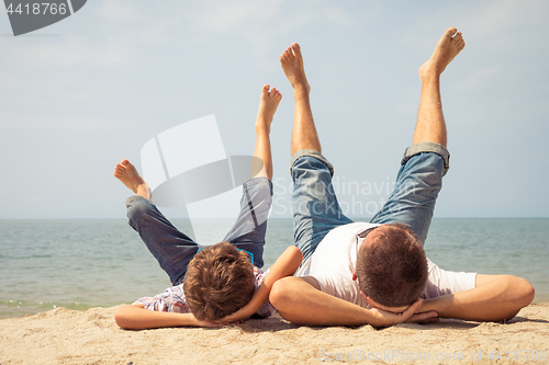 Image of Father and son playing on the beach at the day time.