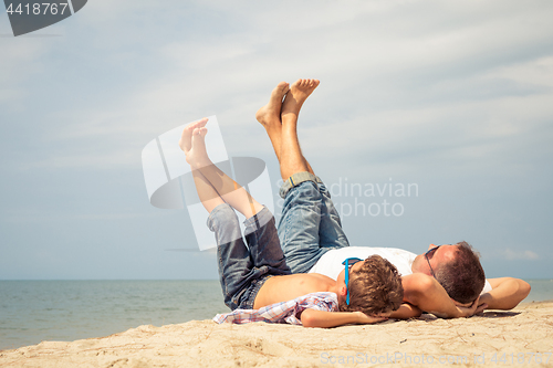 Image of Father and son playing on the beach at the day time.