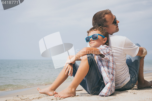 Image of Father and son playing on the beach at the day time.