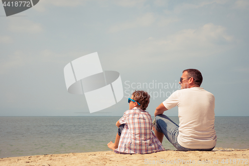 Image of Father and son playing on the beach at the day time.