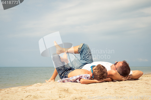 Image of Father and son playing on the beach at the day time.