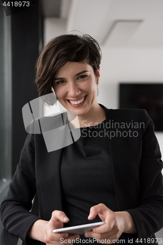 Image of Elegant Woman Using Mobile Phone by window in office building