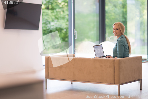 Image of Young woman using laptop at home