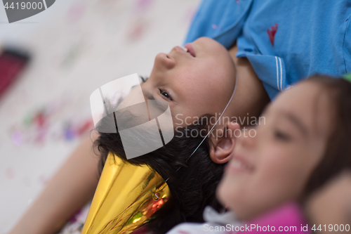 Image of kids  blowing confetti while lying on the floor