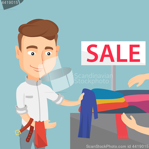 Image of Young man choosing clothes in a shop on sale.