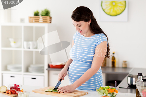 Image of pregnant woman cooking vegetables at home