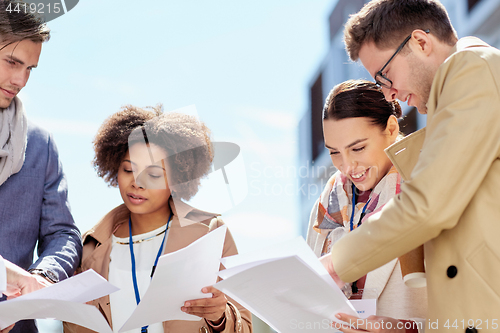 Image of international business team with papers outdoors