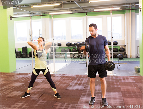 Image of man and woman with kettlebell exercising in gym