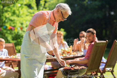 Image of senior man cooking meat on barbecue grill outdoors