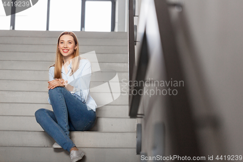 Image of happy smiling woman or student sitting on stairs