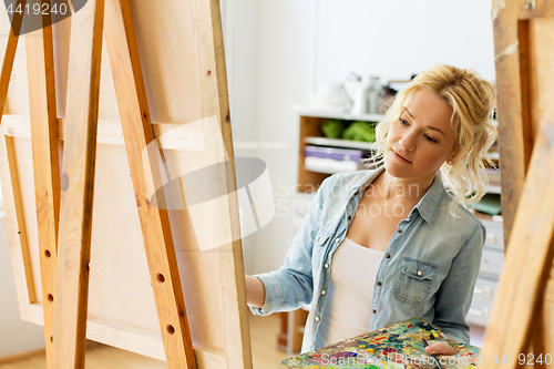 Image of woman with easel painting at art school studio