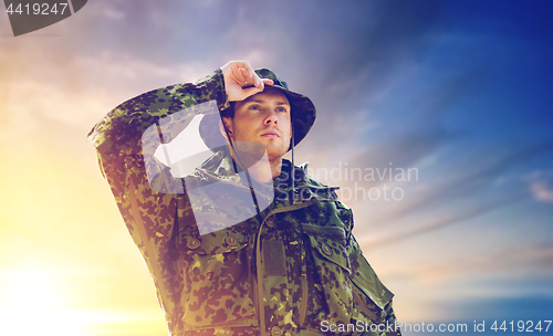 Image of young soldier in military uniform over sky 