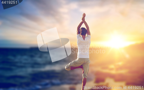 Image of happy man making yoga tree pose over sea