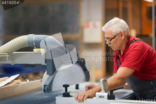 Image of carpenter working with panel saw at factory