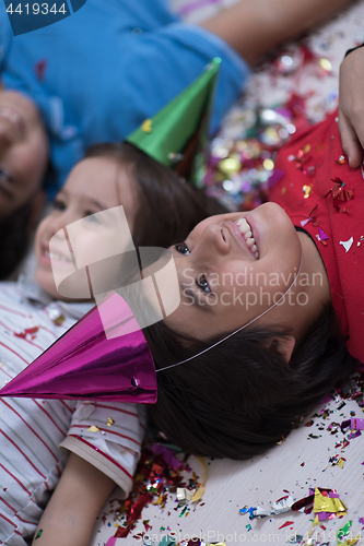 Image of kids  blowing confetti while lying on the floor