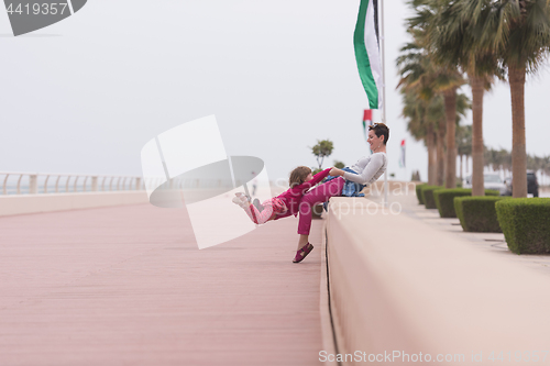 Image of mother and cute little girl on the promenade by the sea