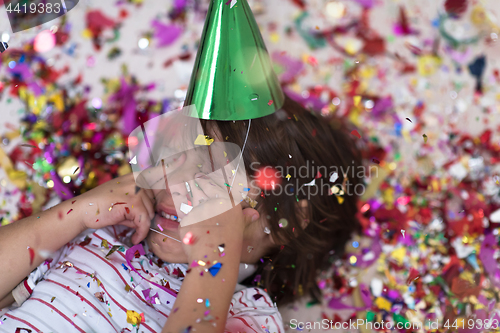 Image of kid blowing confetti while lying on the floor