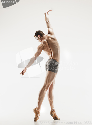 Image of Athletic ballet dancer in a perfect shape performing over the grey background.