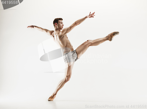 Image of Athletic ballet dancer in a perfect shape performing over the grey background.