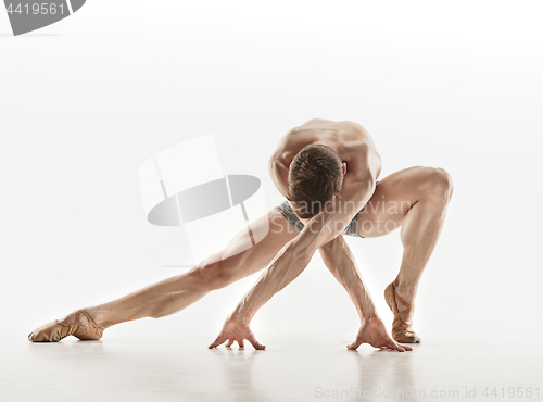 Image of Athletic ballet dancer in a perfect shape performing over the grey background.