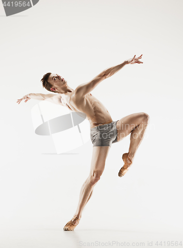 Image of Athletic ballet dancer in a perfect shape performing over the grey background.