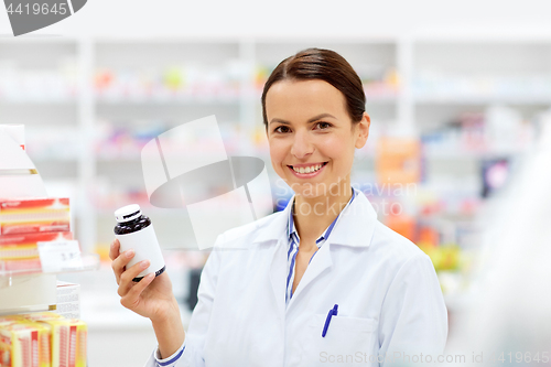 Image of happy female apothecary with drug at pharmacy