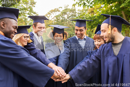 Image of happy students or bachelors in mortar boards