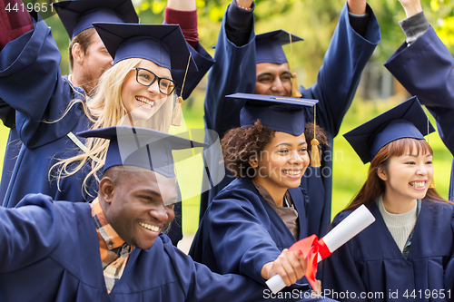 Image of happy students in mortar boards with diplomas