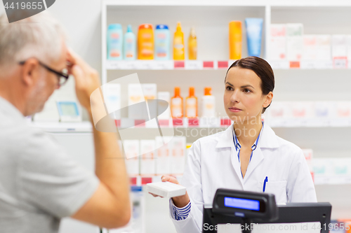 Image of apothecary giving drug to senior man at pharmacy