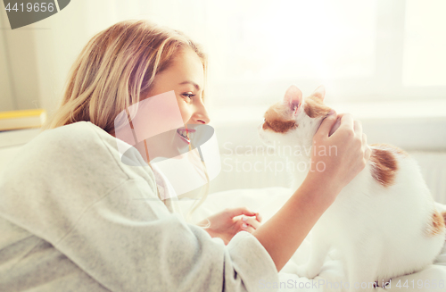 Image of happy young woman with cat in bed at home