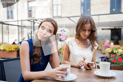 Image of young women with smartphone and coffee at cafe