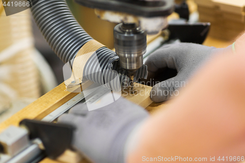 Image of carpenter with drill press and board at workshop