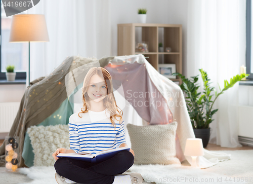 Image of happy smiling girl reading book at home