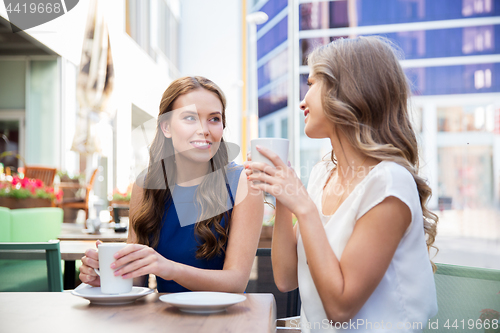 Image of smiling young women drinking coffee at street cafe