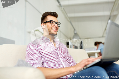 Image of smiling man with laptop working at office