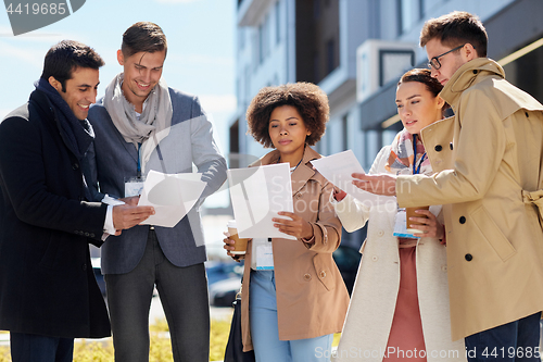 Image of international business team with papers outdoors