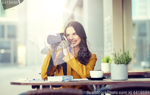 Image of happy tourist woman with camera at city cafe