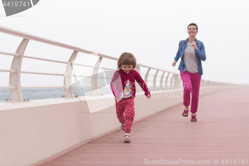 Image of mother and cute little girl on the promenade by the sea