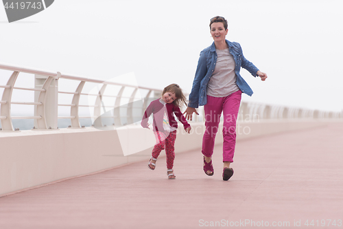 Image of mother and cute little girl on the promenade by the sea