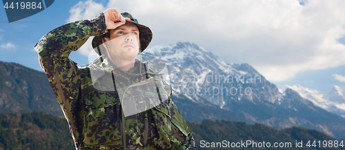 Image of young soldier in military uniform over mountains