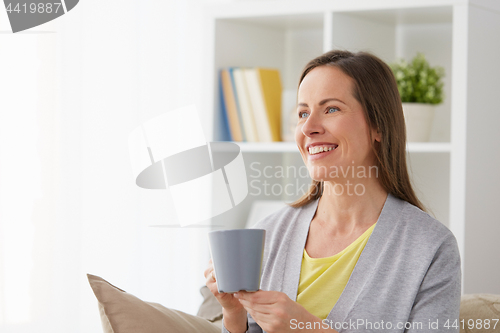 Image of happy woman drinking tea or coffee at home