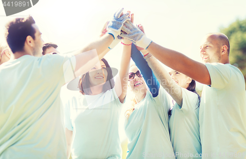 Image of group of volunteers making high five in park