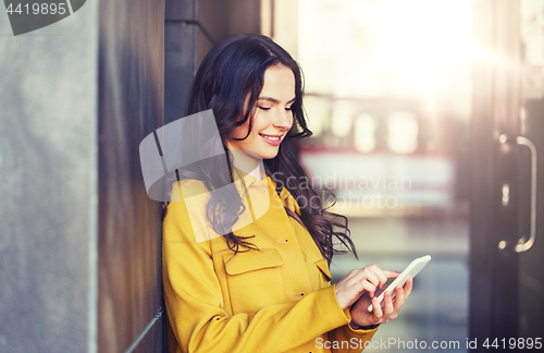 Image of smiling young woman or girl texting on smartphone