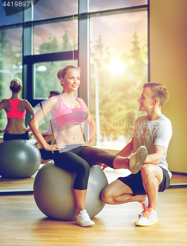 Image of smiling man and woman with exercise ball in gym